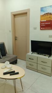 a living room with a tv and a coffee table at انوار عمان - Anwar Amman Hotel in Amman
