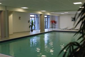 a swimming pool with green water in a building at Résidence Mer & Golf Tourmalet in La Mongie