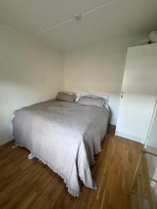 a white bed in a room with a wooden floor at Modern apartment with large balcony in Halmstad