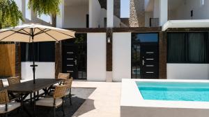 a dining table with an umbrella next to a swimming pool at Suite privada con alberca - Cama Queen in El Centenario