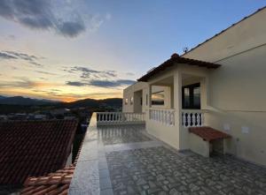 a house with a balcony with a sunset in the background at Pousada Narcizo in São Lourenço