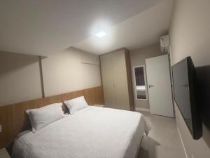 a bedroom with a white bed and a television at View Soft House - Quarto e Sala 213 in Lauro de Freitas +12 photos