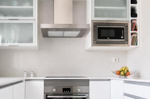 a white kitchen with a microwave and a bowl of fruit at CAROLA l, "Encantador apartamento de estilo marinero a 100m playa Catia" in Ribeira