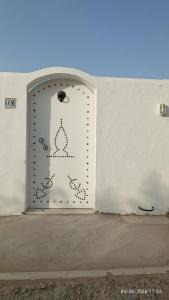 a door in a white wall with a sign on it at Chalet Dar Well-Ness in Dar Mohammed Salah