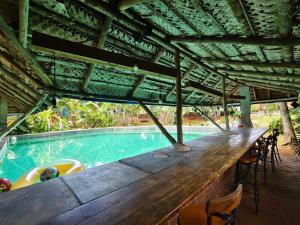 a swimming pool with a wooden bar and chairs at LIVAA NEST Resort Mysore in Kālvādi