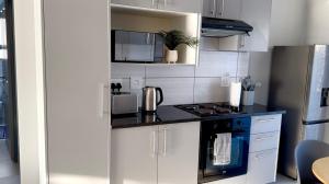 a kitchen with white cabinets and a stove top oven at Nova Apartments- MbabaneCBD in Mbabane