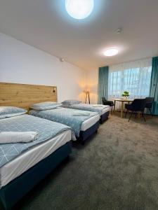 three beds in a room with a table and chairs at DOBA RENT Wysockiego 104 in Białystok +72 photos