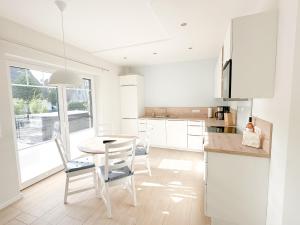 a white kitchen with a wooden table and chairs at Ferienwohnung Knut in Bornholt