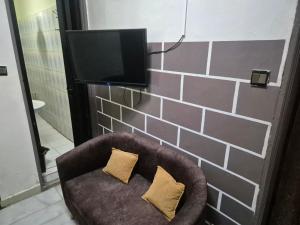 a brown chair with two pillows in front of a tv at SEN-HOME Free in Dakar