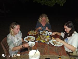 three women sitting at a table eating food at Kuma Surf Camp in Arugam Bay