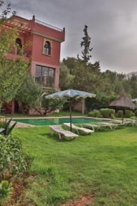 a house with a pool and an umbrella and benches at Dar TOUFTEN in Agouni