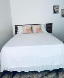 a white bed with two pink pillows on it at FRAN's - HOSPEDAGENS in Lagoa Santa