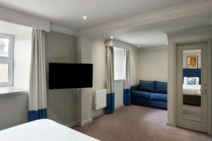a bedroom with a bed and a blue couch at Four Points Flex by Sheraton Nottingham in Nottingham