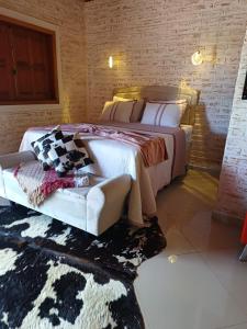 a bedroom with a large bed and a couch at Chalés Maktub 1 in Camanducaia