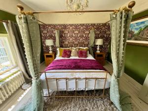 a bedroom with a canopy bed with purple sheets at Liberty House in Ashbourne