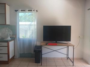 a television on a table in a room with a window at Jambolana Studio in Punaauia