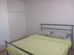 a small bedroom with a bed with green sheets and pillows at Jambolana Studio in Punaauia