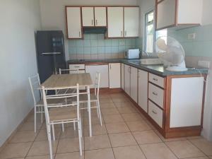 a kitchen with white cabinets and a table and chairs at Jambolana Studio in Punaauia