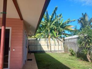 a porch of a house with palm trees and a fence at Jambolana Studio in Punaauia