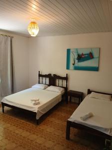 a bedroom with two beds and a painting on the wall at Pousada e Chocolateria Muito Mais in Itaparica