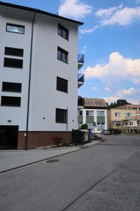 a white building with windows on the side of a street at Oravelle Loft Kubin in Dolný Kubín