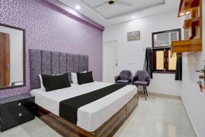 a bedroom with a bed and two purple chairs at Hotel O Rooftop Inn in New Delhi