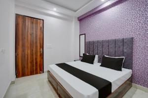 a bedroom with a large bed with a purple wall at Hotel O Rooftop Inn in New Delhi