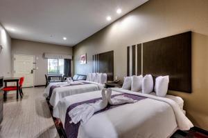 a hotel room with four beds and a desk at Humble Inn & Suites in Humble