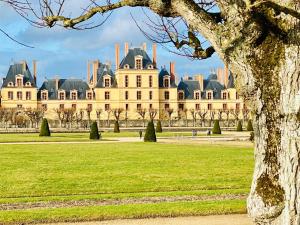 a large building in a park with a tree at Grand Studio Centre Fontainebleau INSEAD - Cocon Deluxe in Fontainebleau