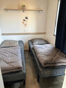 two beds in a small room with at Mobile home climatisé 4 personnes proche Europapark in Vogelgrun