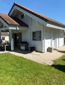 a white house with a patio and a grill at Au P'ti Chalet in Souvans