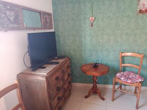 a tv on a dresser with a chair and a table at Chez Annick in Escoeuilles