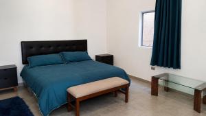 a bedroom with a bed with blue sheets and a glass table at Loft privado con alberca - Cama King in El Centenario +24 photos