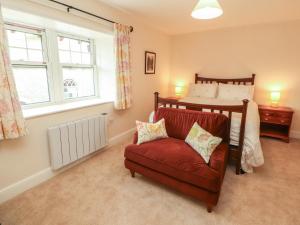 a bedroom with a bed and a red chair at East View in Kirkby Stephen