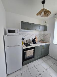 a kitchen with a white refrigerator and a microwave at Charmante maison Marnaise in Vauclerc