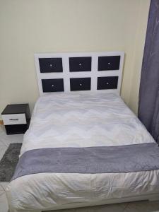 a bedroom with a white bed with a black headboard at Kilima Suites in Taveta