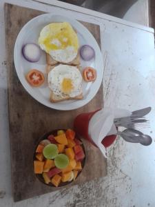 a plate of food with eggs and fruit on a table at Kuma Surf Camp in Arugam Bay