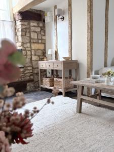 a living room with a table and a stone fireplace at Castle Cottage Winchcombe in Winchcombe