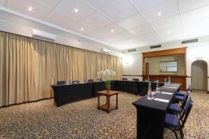 a conference room with long tables and blue chairs at Holiday Inn - Johannesburg Sunnyside Park by IHG in Johannesburg