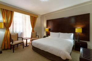 a hotel room with a large bed and a chair at Holiday Inn - Johannesburg Sunnyside Park by IHG in Johannesburg