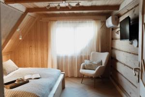 a bedroom with a bed and a chair and a window at Willa Madejówka - Apartamenty z Widokiem na Góry i Wanną z Jacuzzi in Ząb