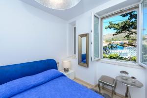 a bedroom with a blue bed and a window at Holiday Home Villa Rosemary in Dubrovnik