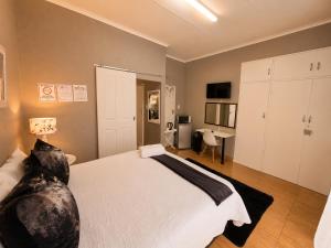 a bedroom with a large white bed and a desk at Zhantique Guest House 2- Unit 5 in Boksburg