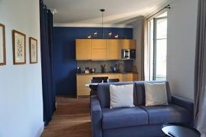 a blue living room with a couch and a kitchen at Maison Constant - Le Camélia in Autun