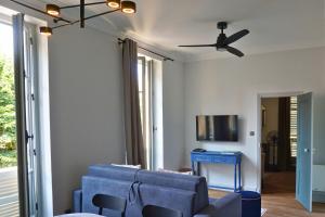 a living room with a blue couch and a ceiling fan at Maison Constant - Le Camélia in Autun