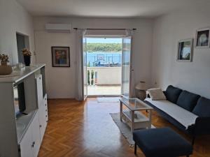 a living room with a blue couch and a large window at Apartment Školj in Posedarje