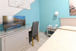 a bedroom with a bed and a desk with a television at Hotel Bristol in Trieste