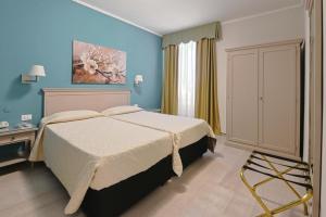 a bedroom with a bed and blue walls at Hotel Bristol in Trieste