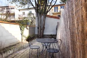 トゥールーズにあるNouvel Oasis Toulouse Saint Cyprienの木の横に座るテーブルと椅子2脚