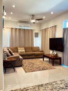 a living room with a couch and a flat screen tv at The Ansen Place in Belmopan